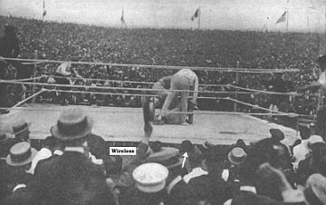 Photo from ringside also showing part of immense crowd.  Carpentier is down for the count here.  Radio broadcaster is located at the tip of the white arrow.  Photo from, ‘Wireless Age’, August 1921.