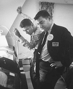 Peter Lawford & Pierre Salinger following teletype returns, election night, Nov 1960.