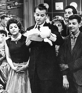 Dick Clark on the "American Bandstand" TV show from Philadelphia, appears with teens around him as he reads mail. AP photo.