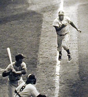 1955 World Series: Jackie Robinson of the Brooklyn Dodgers charges home plate and catcher Yogi Berra.