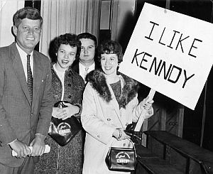 Nov. 12, 1959: JFK, with students at River Falls State College, Wisconsin, appears unfazed by signmaker’s difficulty with his name (University of Wisconsin-River Falls Archives).
