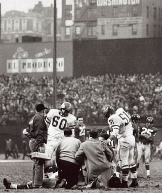 Chuck Bednarik & Chuck Webber, No. 51, hover around the injured Frank Gifford as trainers attend to him on the field.