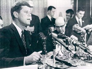 Jan 21, 1960: JFK at a press conference in Milwaukee, WI, where he announced he would run in the state’s April 5th, 1960 primary against Sen. Hubert Humphrey. Kennedy aide, Pierre Salinger, is seen in the back-ground, far right, reading from paper.  Photo, UPI. 