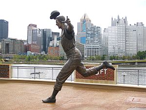 Bill Mazeroski World Series statue shown against Pittsburgh skyline along the Allegheny River at PNC Park.