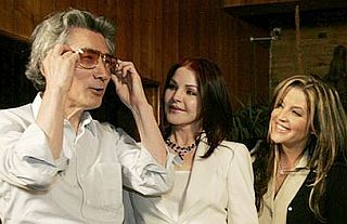 July 2006: Prime Minister Koizumi is excited to try on a pair of Elvis sunglasses as Priscilla & Lisa Marie Presley look on. 
