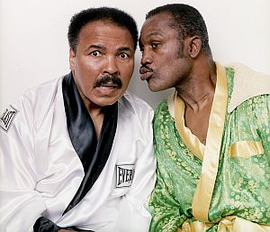 2003: Muhammad Ali & Joe Frazier pictured in their 1971 robes at Joe Frazier’s Philadelphia Gym; Frazier shown here in a forgiving pose. (Walter Iooss Jr./SI).