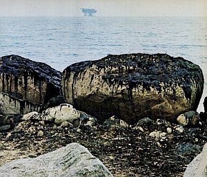 1969: Life magazine photo of oil-stained boulders with oil rig on the far horizon. Boulders located at Santa Claus, south of Santa Barbara. Photo, Harry Benson.