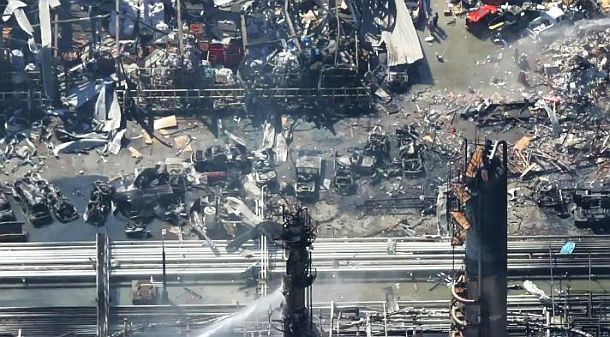 Aerial view of blast & fire damage at BP’s Texas City, Texas refinery sometime after the March 2005 explosion and fires, showing severely damaged structure in the upper left and burnt-out hulks of several vehicles at center of photo.
