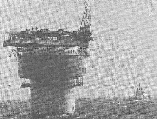 Four Greenpeace occupiers aboard the Brent Spar, upper left, celebrate on helicopter pad waving lit flares at the news that the Brent Spar was heading a new direction toward shore, and would not be dumped at sea.