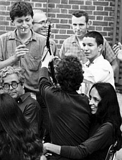 ...More of the same with Dylan turning toward fans, on Joan’s lap. Photos by David Gahr.