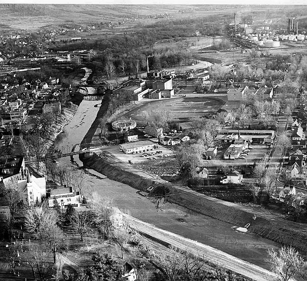 This 1950s aerial photo shows the town of Wellsville, NY and the Genesee River in the foreground, and also in the distance, upper right, the Sinclair Oil Refinery, then still operating.