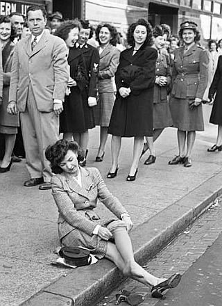 Woman at curbside putting on a pair of  nylon stockings in Wash., DC, Oct 1945,  having scored a pair during post-WWII limited supply.